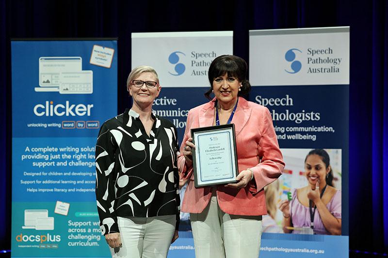 This is a photo of Professor Elizabeth Cardell holding a Fellowship plaque as she poses with Emma Power to her left at the SPA 2026 Conference. Emma has short blonde hair and is wearing a black and white shirt with white pants. Elizabeth has short black hair and is wearing a peach blazer and white pants. This is a photo of Professor Elizabeth Cardell holding a Fellowship plaque as she poses with Emma Power to her left at the SPA 2026 Conference. Emma has short blonde hair and is wearing a black and white shirt with white pants. Elizabeth has short black hair and is wearing a peach blazer and white pants.