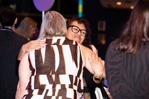 Two attendees embracing, with one smiling. 