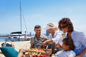 A group of people relaxing on the beach, sharing a platter of food. Source: Destination Gold Coast