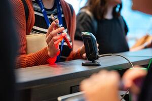An attendee's hand holding their phone up to scanner at the registration desk.